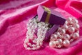 Purple box with pink pearl strings on a crimson velvet Royalty Free Stock Photo