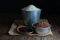 Purple-brown rice in a wooden ladle, jasmine rice in a zinc bucket, jasmine red rice in a zinc cup placed on sackcloth on a rustic Royalty Free Stock Photo