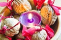 Purple candle with decorated wallnuts in a wooden bowl