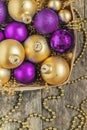 purple Christmas balls and gold, beads lie in a wooden basket to Royalty Free Stock Photo