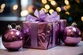 purple christmas gift box with two ornaments on a table in front of a christmas tree Royalty Free Stock Photo