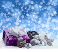 Purple Christmas package , gift of a silver ribbon. Jingle bells , silver christmas balls and christmas stars put on snow. Royalty Free Stock Photo