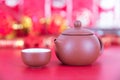 Purple clay milk pot and tea bowl on red background. The Chinese characters in the picture mean `happiness`