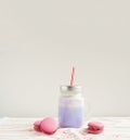 Purple coffee in stylized mason jar cup with macarons and colorful decoration. Blueberry milk shake, cocktaill, frappuccino. Unico