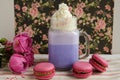 Purple coffee in stylized mason jar cup with macarons and roses and colorful decoration on background of floral pattern. Blueberry Royalty Free Stock Photo