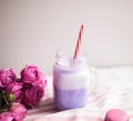 Purple coffee in stylized mason jar cup with macarons and roses and colorful decoration. Blueberry milk shake. Unicorn coffee. Royalty Free Stock Photo