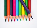 Purple color wood pencil crayon placed on top of a row of different color wood pencil Royalty Free Stock Photo