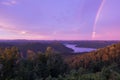 A Purple Colored Sky with a Rainbow at Sunset over Mountain Lake