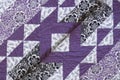 Purple coloured handmade patchwork bed quilt with various fabric geometric patterns