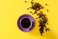 Purple cup of coffee with coffee beans on yellow background Royalty Free Stock Photo