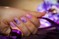 Purple design of nails with patterns of flowers and ribbon. Royalty Free Stock Photo