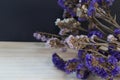 Purple dried flower bouquet on wooden floor against black background