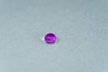 a purple drop of water looking like a glowing stone on top of a sheet of white fabric. Royalty Free Stock Photo