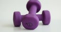 Purple dumbbells of 1 kg spinning on white background closeup 4k movie