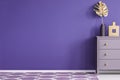 Purple empty wall in a room interior with a chest of drawers wit