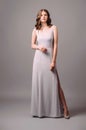 Purple evening dress with front slit. Luxury female gown. Young adult elegant lady in high heels, studio shot. Bridesmaids violet