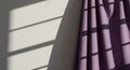 Purple fabric curtain with soft folds hangs against a wall, casting shadows. Light from Royalty Free Stock Photo