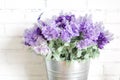 Purple fabric lavender flowers in bucket on white brick wall