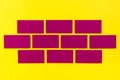 Purple flat rectangles mimic brickwork on yellow cardboard. Top view