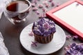 Purple floral cupcake using trendy Escapism trend. Frame mock up, cup of coffee among lilac flowers