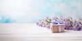 Purple flowers and a gift box on a wooden table, blue background, copyspace Royalty Free Stock Photo