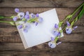 Purple flowers irises and a sheet of paper on a wooden background