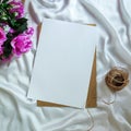 Flowers, piece of blank paper (invitation card mockup), and jute cord for knitting on a white cloth Royalty Free Stock Photo