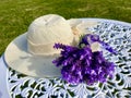 Purple French Lavender And Beige Woven Hat On A White Wrought Iron Round Table.