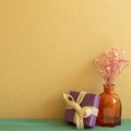 Purple gift box and dry flowers on wooden table. khaki brown wall background Royalty Free Stock Photo