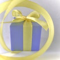 Purple Gift box at the end of the spiral yellow ribbon, white background, square. Royalty Free Stock Photo