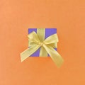 Purple gift box on orange color background, square.