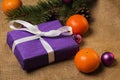 Purple gift with white ribbon and Christmas decorations Royalty Free Stock Photo