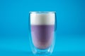 Purple goji matcha on blue background. Matcha cocktail in double glass cup. Royalty Free Stock Photo