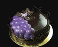 Purple grapes and chocolate cake decorated with chocolate vines border on golden coaster Royalty Free Stock Photo