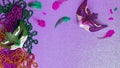 Purple and green carnival masks, feathers and shiny beads, traditional carnaval accessories. Mardi gras frame or border on purple Royalty Free Stock Photo