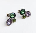 Purple and green crystal vintage earrings on beige background, statement retro jewelry for women Royalty Free Stock Photo
