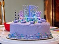 Purple happy birthday cake with on lit candles on it Royalty Free Stock Photo