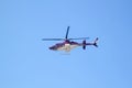 Purple helicopter tour flies against background of clear blue sky. Photo of a flying vehicle with blurred rotating blades