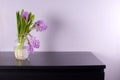 Purple hyacinth in glass vase on black chest