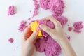 Purple kinetic sand in hand isolated on a white background. Colored sand for modeling for children