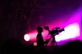 Purple lights on stage behind a cameraman filming live