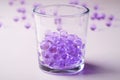 Purple marbles in drinking transparent glass with scattered marbles on white background Royalty Free Stock Photo