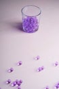 Purple marbles in drinking transparent glass with scattered marbles on white background Royalty Free Stock Photo