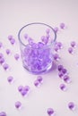 Purple marbles in drinking transparent glass with scattered marbles on white background Royalty Free Stock Photo