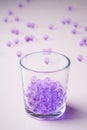 Purple marbles in drinking transparent glass with scattered marbles on white background Royalty Free Stock Photo