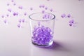 Purple marbles in drinking transparent glass with scattered marbles on white background Royalty Free Stock Photo