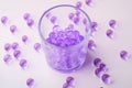 Purple marbles in drinking transparent glass with scattered marbles on white background Royalty Free Stock Photo