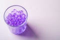 Purple marbles in drinking transparent glass on white background Royalty Free Stock Photo