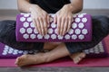 Purple massage acupuncture pillow and white massage tips in female hands.