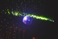 Purple mirror ball for the dance floor of a nightclub reflects the rays of light